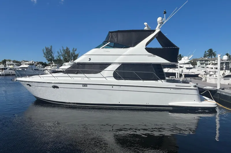 The Image of 2003 Carver 450 Voyager Pilothouse yacht docked at marina under clear blue sky. - 0
