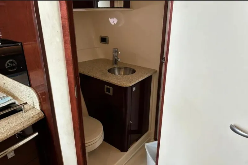 Slide: The Image of 2008 Sea Ray 38 Sundancer bathroom with sink and toilet, featuring wood cabinetry and granite countertop. - 21