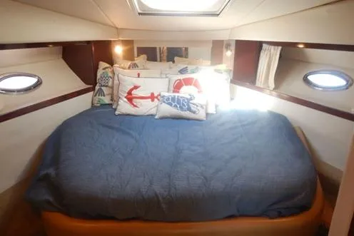 Slide: The Image of 2008 Sea Ray 380 Sundancer cabin with nautical-themed bedding and porthole windows. - 25