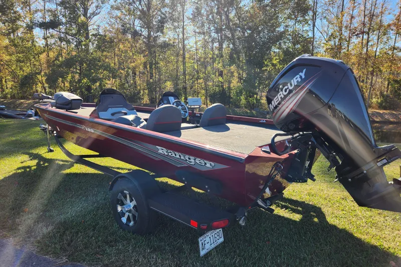 Slide: The Image of 2016 Ranger RT188 boat with Mercury engine on grassy area, surrounded by trees. - 2