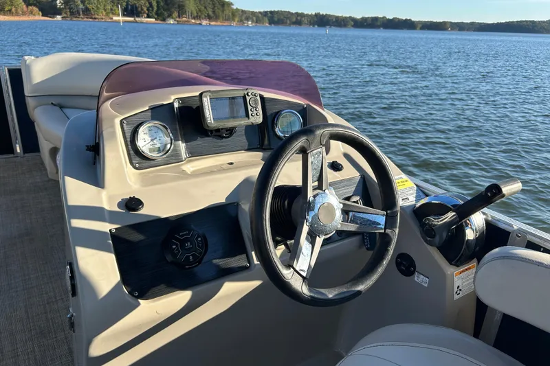 Slide: The Image of Cypress Cay Seabreeze 232 boat dashboard with steering wheel, controls, and lake view. - 12