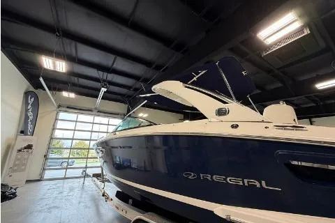 Slide: The Image of 2020 Regal 2800 Bowrider boat in showroom, blue and white exterior, indoor lighting. - 2