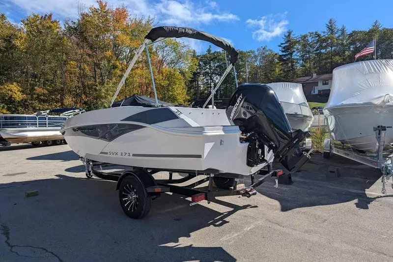 Slide: The Image of 2026 Starcraft SVX 171 OB boat on trailer, parked outdoors, surrounded by trees. - 2