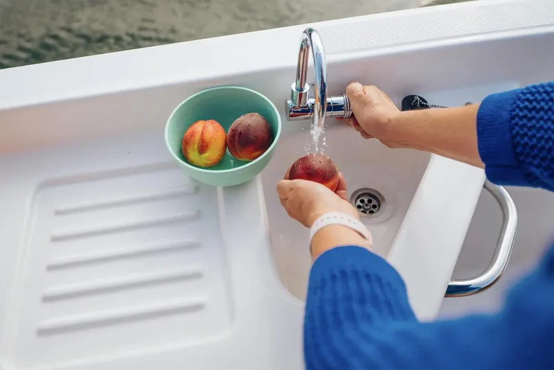 Slide: The Image of Manufacturer Provided Image: Person washing peaches on Bayliner D22 boat sink, 2025 model. - 6