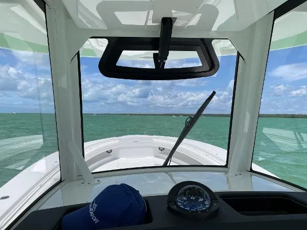 Slide: The Image of 2021 Regulator 34 boat interior with ocean view, compass, and blue cap on dashboard. - 19