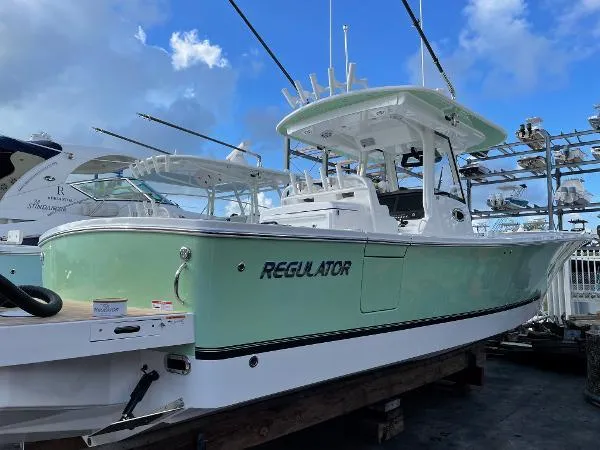 Slide: The Image of 2021 Regulator 34 boat with mint green hull, docked under a blue sky. - 24