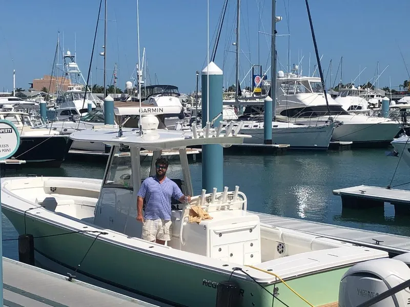 Slide: The Image of 2021 Regulator 34 boat docked at marina with person onboard, surrounded by other boats. - 6