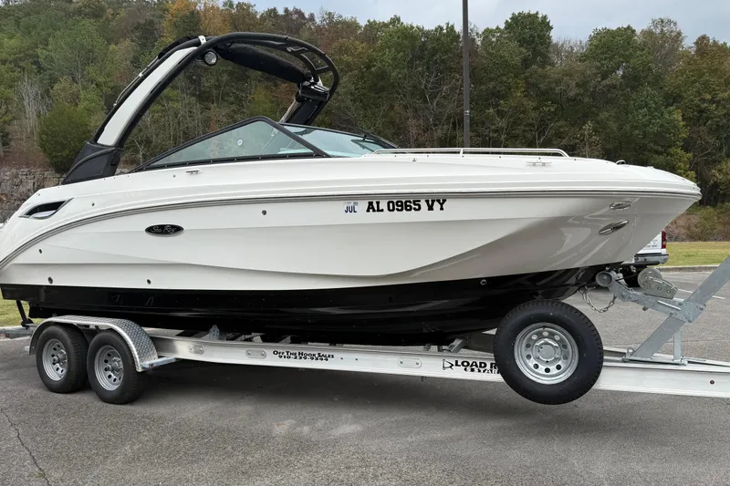 Slide: The Image of 2021 Sea Ray SDX 250 boat on trailer, parked outdoors with trees in background. - 16