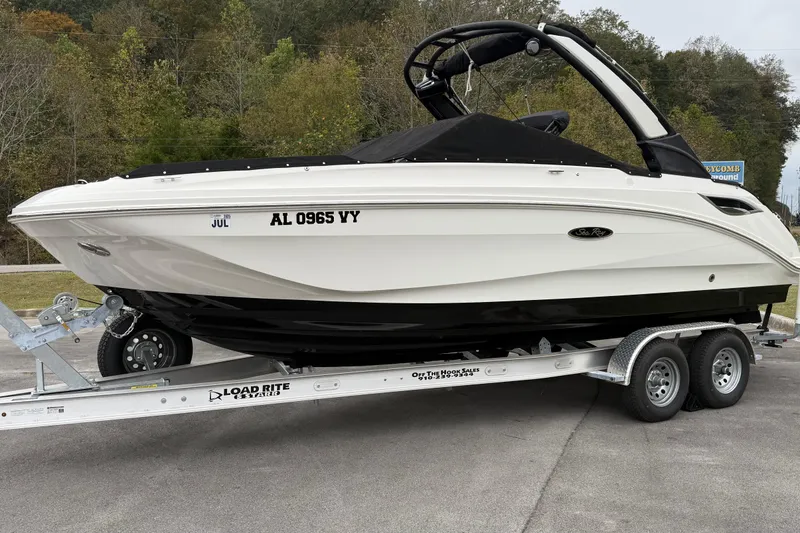 Slide: The Image of 2021 Sea Ray SDX 250 boat on trailer, parked outdoors with trees in background. - 17