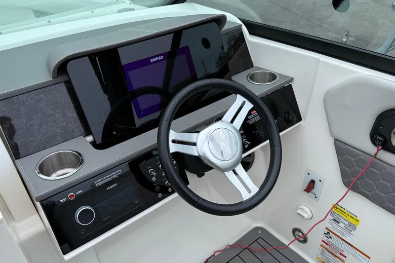 Slide: The Image of 2021 Sea Ray SDX 250 helm with steering wheel, Simrad display, and control panel. - 4