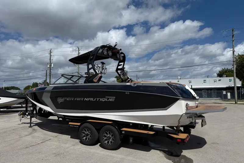 Slide: The Image of 2018 Nautique Super Air Nautique G25 Coastal Edition boat on trailer under cloudy sky. - 4