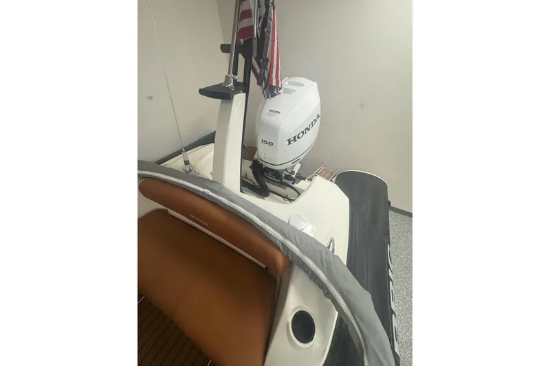 Slide: The Image of 2020 Brig Eagle 6.7 boat with Honda outboard motor, featuring brown seating and American flag. - 6