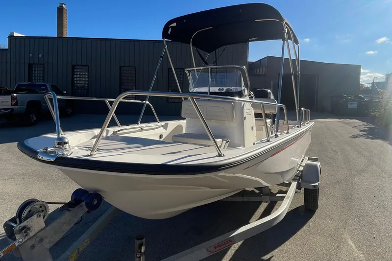 The Image of 2021 Boston Whaler 150 Montauk boat on trailer, parked outdoors under clear sky. - 0