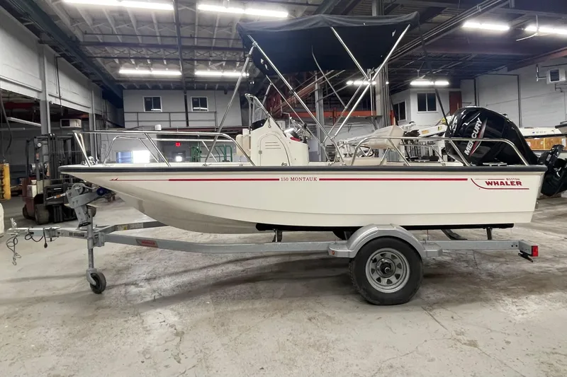 Slide: The Image of 2021 Boston Whaler 150 Montauk boat on trailer in indoor storage facility. - 2