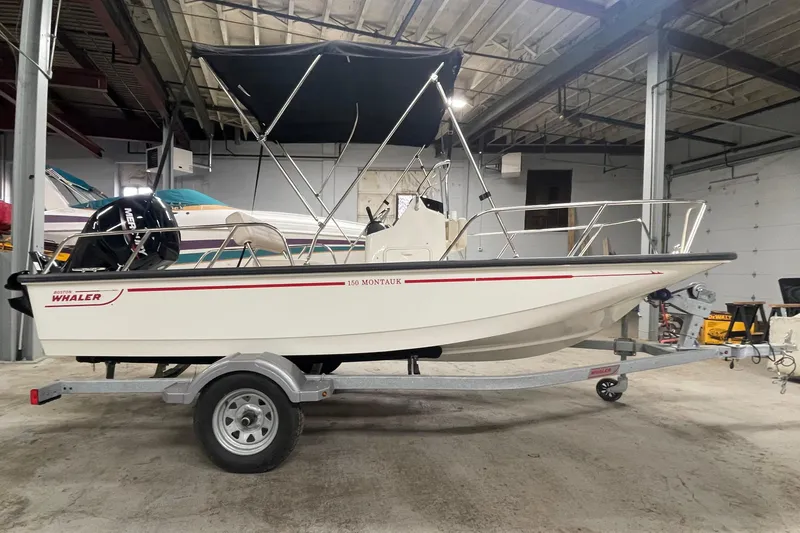 Slide: The Image of 2021 Boston Whaler 150 Montauk boat on trailer in indoor storage. - 3