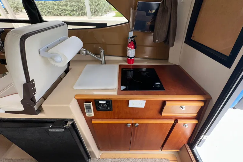 Slide: The Image of 2016 Cutwater C-24 Coupe interior kitchen with stove, sink, and storage cabinets. - 7