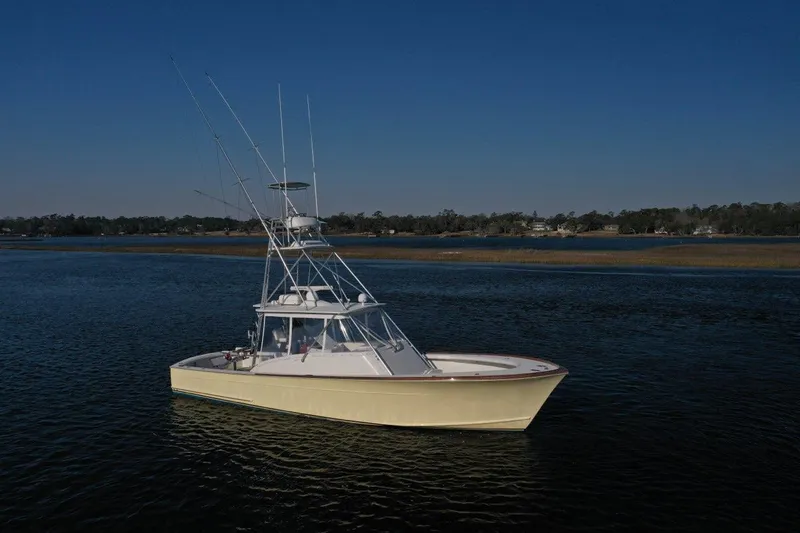 Slide: The Image of 2007 Gamefisherman 42 Walkaround boat on calm water under clear blue sky. - 0
