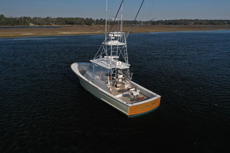 Slide: The Image of 2007 Gamefisherman 42 Walkaround boat on calm water under clear blue sky. - 2