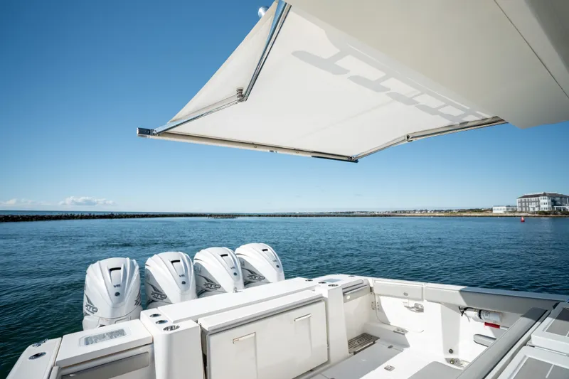 Slide: The Image of 2023 Pursuit S 428 Sport boat with four engines, open water view, and retractable canopy. - 25