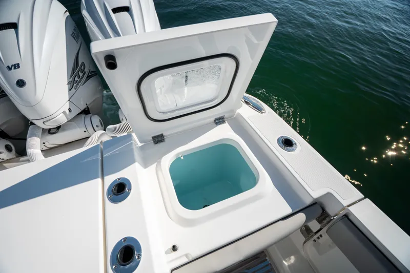 Slide: The Image of 2023 Pursuit S 428 Sport boat with open storage compartment and twin engines on water. - 26