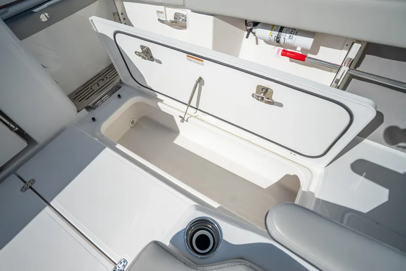 Slide: The Image of 2023 Pursuit S 428 Sport boat storage compartment with open hatch and fire extinguisher. - 31