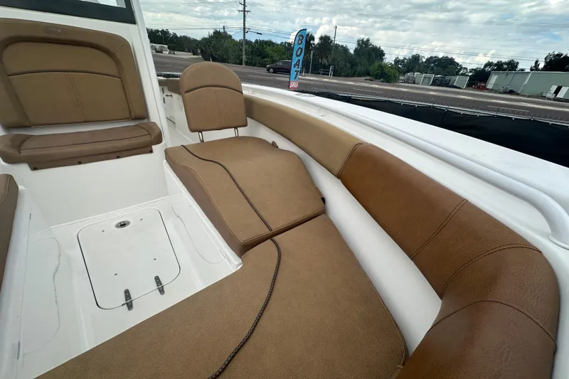 Slide: The Image of 2020 Sea Hunt Ultra 255 SE boat interior with tan seating, parked near a road. - 100