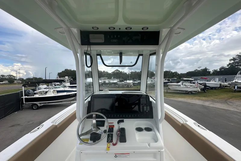 Slide: The Image of 2020 Sea Hunt Ultra 255 SE boat interior with helm and seating, docked under cloudy skies. - 37