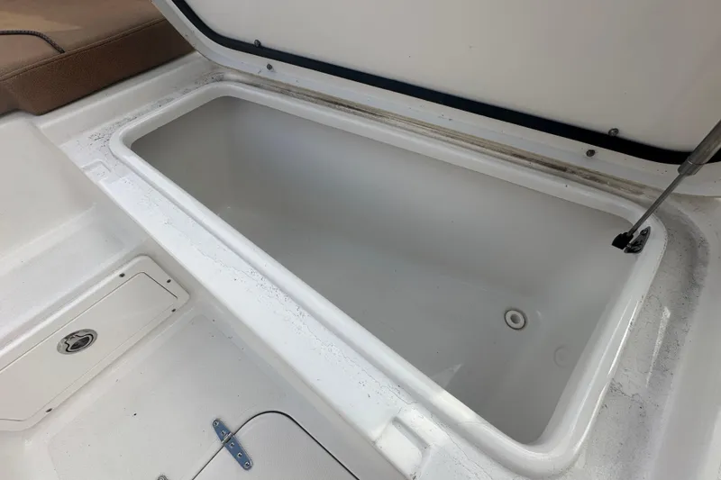 Slide: The Image of 2020 Sea Hunt Ultra 255 SE boat interior with storage compartment and cushioned seating. - 85