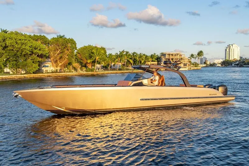 The Image of 2023 DeKoning 43 luxury boat cruising on a scenic waterway at sunset. - 0