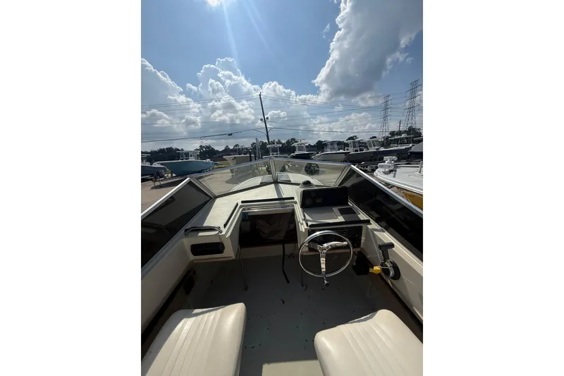 Slide: The Image of 1980 Boston Whaler Revenge 20 boat interior with steering wheel, under a sunny sky. - 12