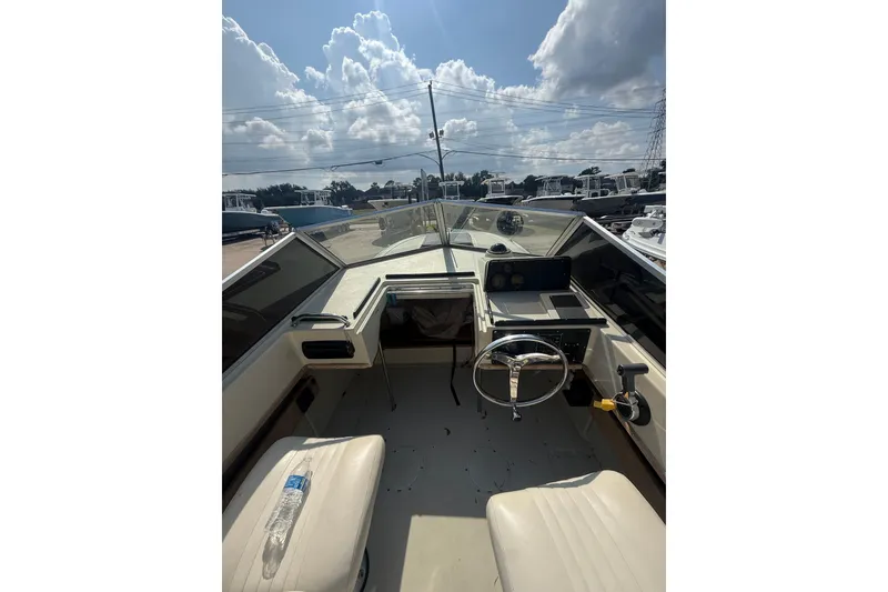 Slide: The Image of 1980 Boston Whaler Revenge 20 boat interior with steering wheel and seating under a cloudy sky. - 14