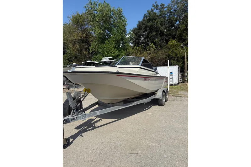 Slide: The Image of 1980 Boston Whaler Revenge 20 boat on trailer, parked outdoors with trees in background. - 3