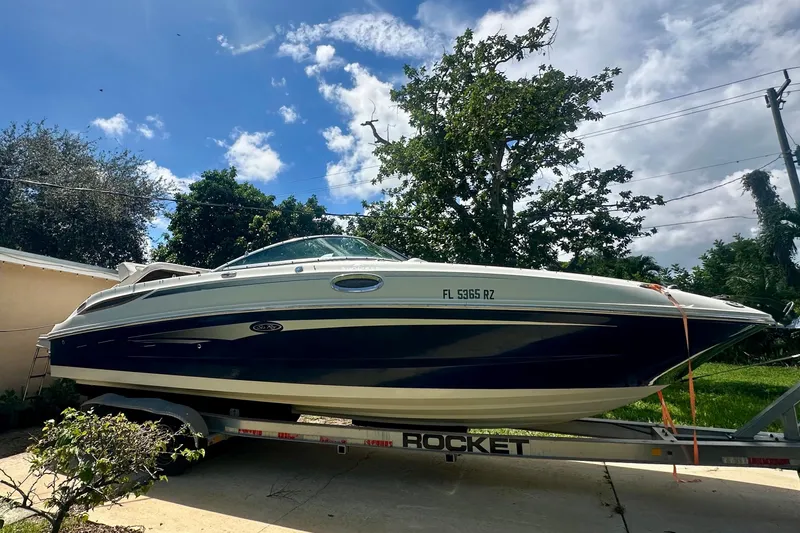 The Image of 2010 Sea Ray 280 Sundeck boat on trailer, parked outdoors under a blue sky. - 0