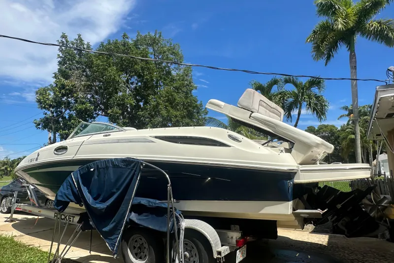 Slide: The Image of 2010 Sea Ray 280 Sundeck boat on trailer, surrounded by palm trees and clear blue sky. - 2
