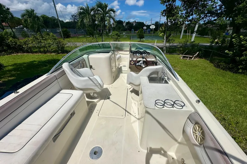 Slide: The Image of 2010 Sea Ray 280 Sundeck boat interior with seating, steering wheel, and lush green surroundings. - 23