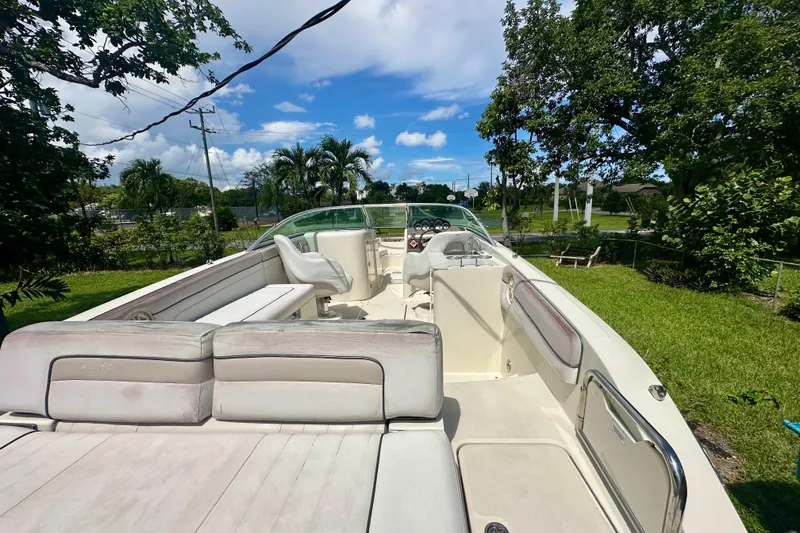 Slide: The Image of 2010 Sea Ray 280 Sundeck boat with spacious seating, parked on grassy area under blue sky. - 24