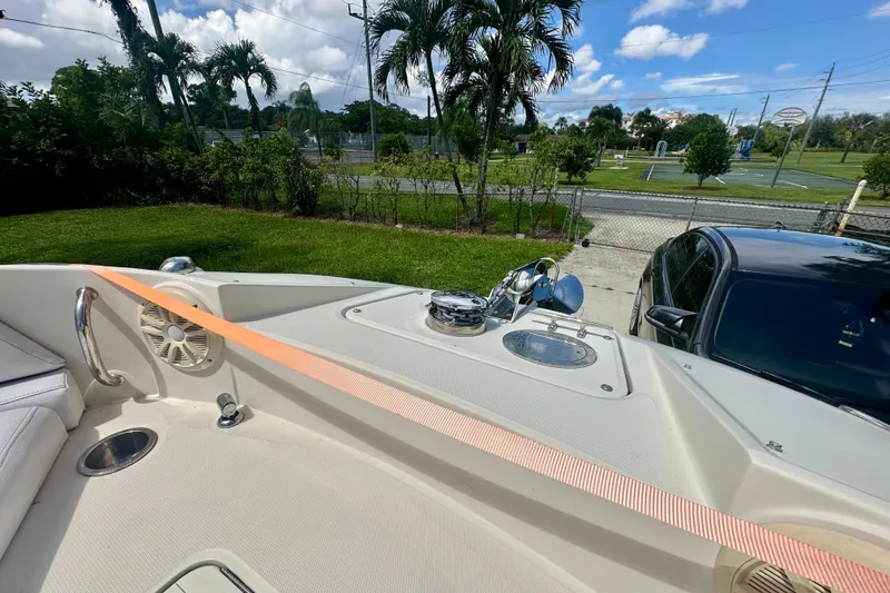 Slide: The Image of 2010 Sea Ray 280 Sundeck boat parked near a car, surrounded by greenery. - 25