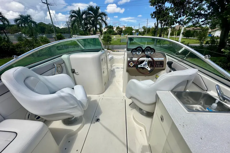 Slide: The Image of 2010 Sea Ray 280 Sundeck interior with white seating, steering wheel, and sink. - 8