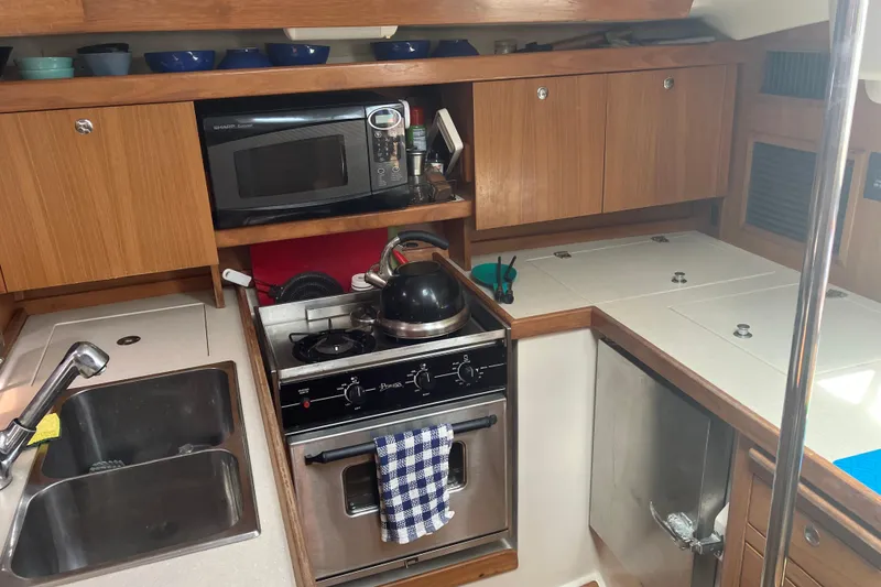 Slide: The Image of Compact kitchen in a 2008 Catalina 350 MkII sailboat with stove, microwave, and sink. - 3