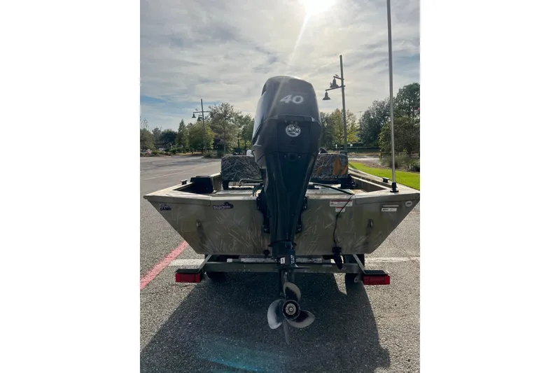 Slide: The Image of 2012 Tracker Grizzly 1754 SC boat with 40 HP motor in a parking lot. - 2