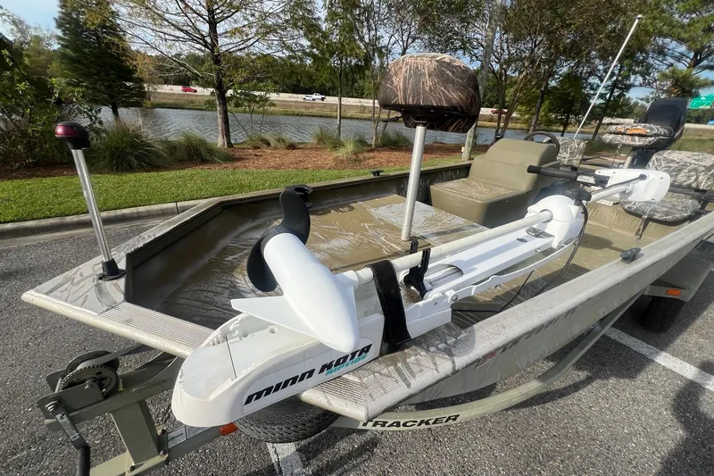Slide: The Image of 2012 Tracker Grizzly 1754 SC boat with Minn Kota trolling motor, parked near a scenic lake. - 4