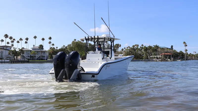 Slide: The Image of 2022 Yellowfin 32 Offshore boat cruising on a sunny day with palm trees in the background. - 10