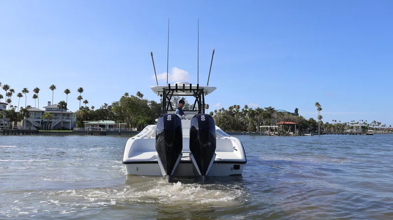 Slide: The Image of 2022 Yellowfin 32 Offshore boat on water with twin engines, palm trees in background. - 11