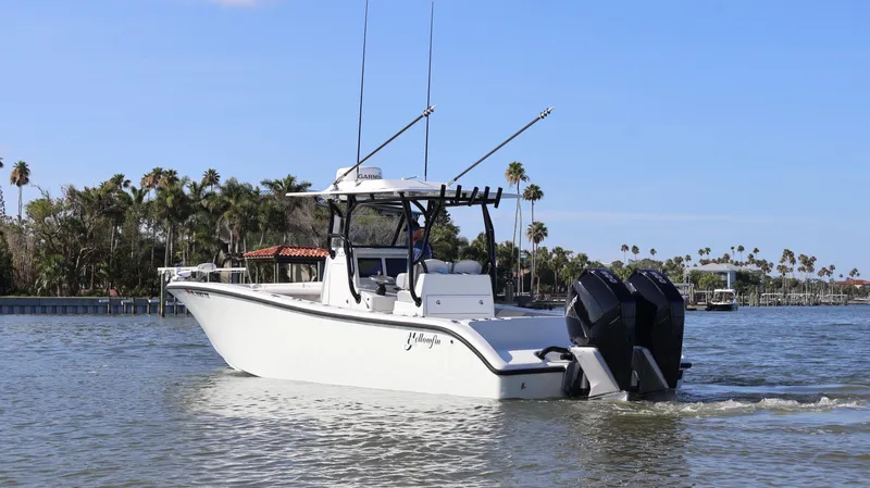 Slide: The Image of 2022 Yellowfin 32 Offshore boat cruising on a calm waterway with palm trees in the background. - 4