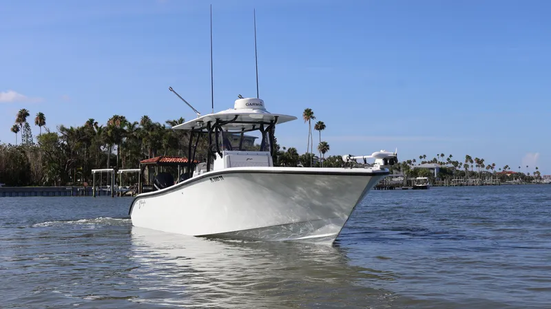 Slide: The Image of 2022 Yellowfin 32 Offshore boat cruising on a sunny day with palm trees in the background. - 7