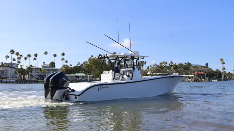 Slide: The Image of 2022 Yellowfin 32 Offshore boat cruising on a calm waterway with palm trees in the background. - 9
