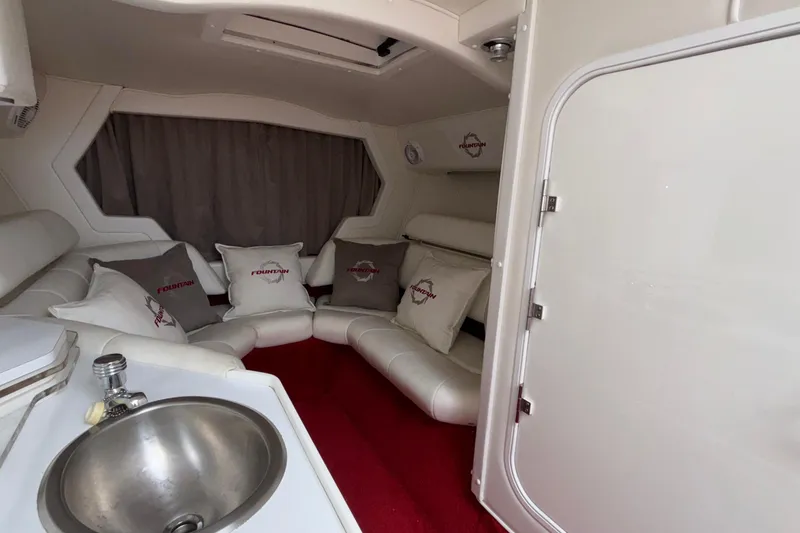 Slide: The Image of 2007 Fountain 38 Lightning boat interior with white seating, pillows, and a small sink. - 30