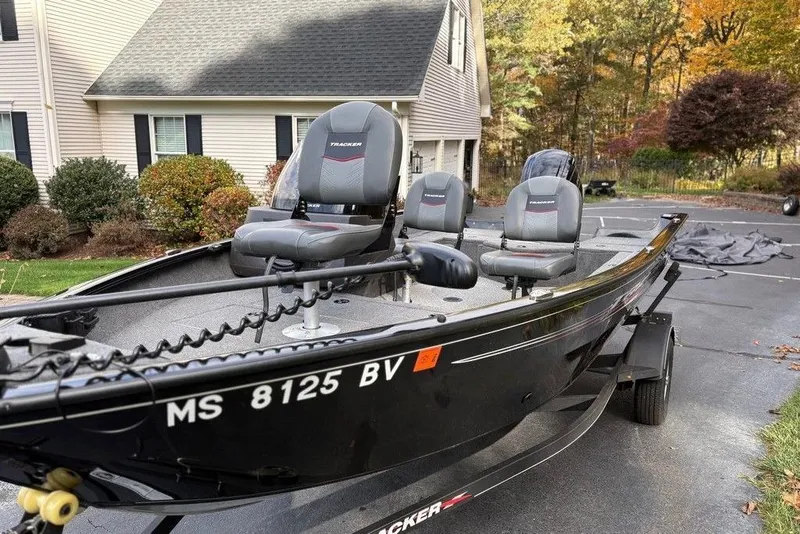 Slide: The Image of 2023 Tracker Pro Guide V-16 SC boat parked in driveway, surrounded by autumn foliage. - 6