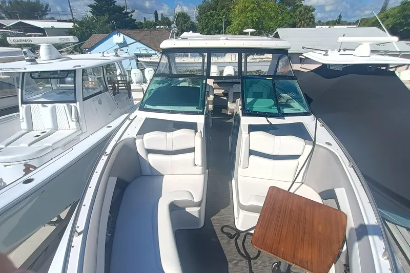 Slide: The Image of 2019 Four Winns H350 boat with spacious seating and wooden table, docked among other boats. - 2