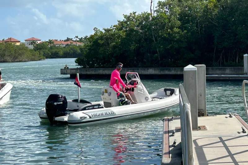 The Image of 2023 Highfield Sport 560 boat navigating a scenic waterway near a dock. - 1